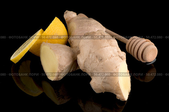 Ginger root drizzler with honey and lemon on black reflective background. Concept of natural ingredients to prevent colds. Стоковое фото, агентство Ingram Publishing / Фотобанк Лори