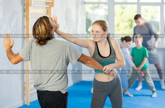 Girl and man in group self-defense classes practicing sparring technique of blowing to chin in gym. Стоковое фото, фотограф Яков Филимонов / Фотобанк Лори