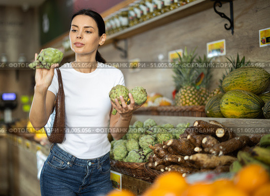 Girl client near vegetable stand in store choose artichoke. Стоковое фото, фотограф Яков Филимонов / Фотобанк Лори