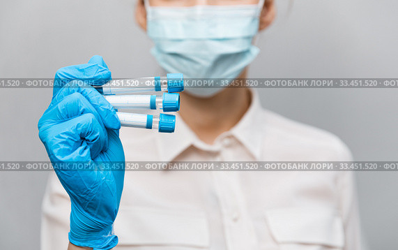 Girl Doctor in medical mask and rubber gloves, holds in her hands, closeup of test tube with tests for the presence of covid-19. Doctor in medical clothes demonstrates test tubes with coronavirus. Стоковое фото, фотограф Сергей Тимофеев / Фотобанк Лори
