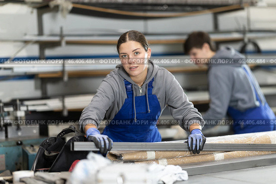 Girl glazer employee in blue overall works in glass processing shop. Стоковое фото, фотограф Яков Филимонов / Фотобанк Лори