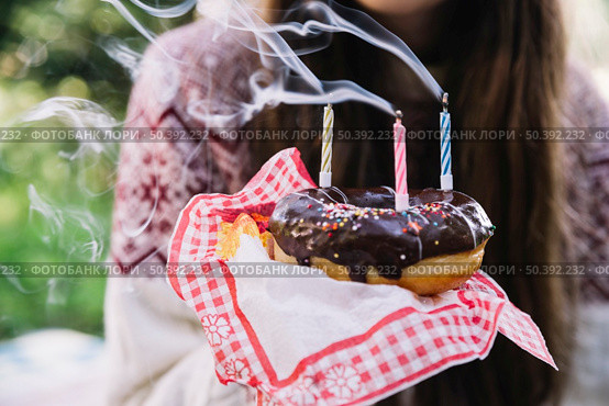 girl holding chocolate donut with extinguish candles. Стоковое фото, агентство Ingram Publishing / Фотобанк Лори