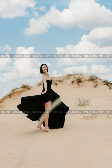 girl in a black long dress in a sandy desert under a blue sky. Стоковое фото, агентство Ingram Publishing / Фотобанк Лори