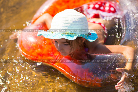 Girl in a hat swimming in the river with a transparent inflatable circle in the shape of a heart with orange feathers inside.The sea with a sandy bottom. Beach holidays, swimming, tanning, sunscreens. Стоковое фото, фотограф Ольга Симонова / Фотобанк Лори