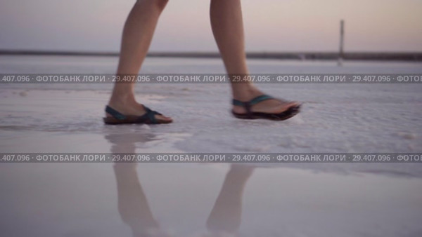 girl in green sandals splash through the puddles of salt lake at sunset time. Стоковое видео, видеограф Ирина Мойсеева / Фотобанк Лори