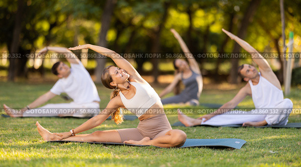 Girl leading outdoor group yoga class in summer park. Стоковое фото, фотограф Яков Филимонов / Фотобанк Лори