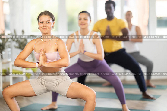 Girl performing Goddess Pose with hands in namaste in yoga class. Стоковое фото, фотограф Яков Филимонов / Фотобанк Лори