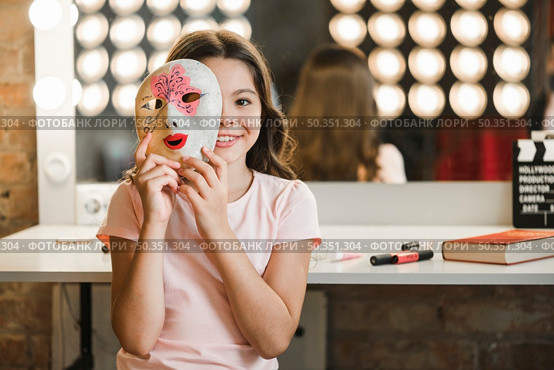 girl sitting backstage holding venetian mask front her face. Стоковое фото, агентство Ingram Publishing / Фотобанк Лори