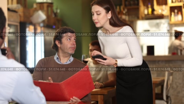 Girl waiter communicates with male customer, serve couple in restaurant. Стоковое видео, видеограф Яков Филимонов / Фотобанк Лори