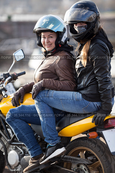 Girlfriend a passenger sitting behind female motorcyclist on a motorbike, cheerful females riding on the urban streets. Стоковое фото, фотограф Кекяляйнен Андрей / Фотобанк Лори