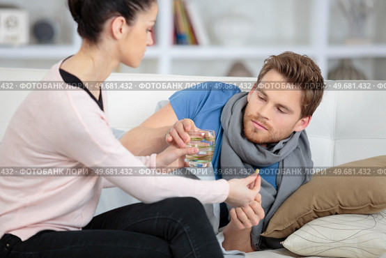 girlfriend taking care of ill boyfriend on the sofa. Стоковое фото, агентство Ingram Publishing / Фотобанк Лори