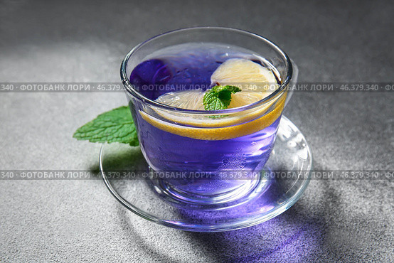 Glass cup of organic butterfly tea and lemon on grey background, closeup. Стоковое фото, фотограф Pixel_shot / Фотобанк Лори
