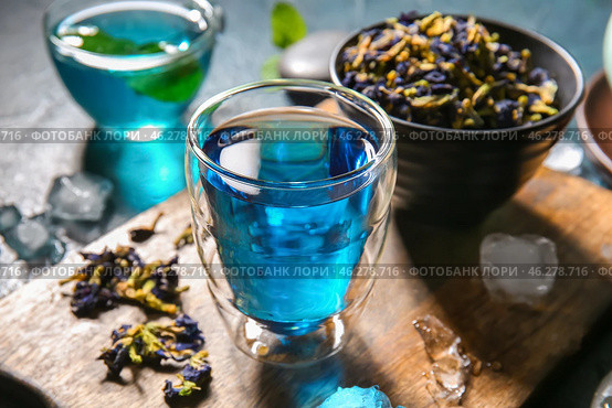 Glass of organic blue tea and dried flowers on table, closeup. Стоковое фото, фотограф Pixel_shot / Фотобанк Лори