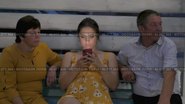 Gomel, Belarus - 25 July 2021: People on bench in an evening park. Pregnant young woman looks at her smartphone. Стоковое видео, видеограф Дмитрий Нечаев / Фотобанк Лори