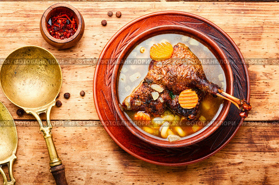 Goose soup with vegetables and pasta. A bowl of duck soup on wooden table. Appetizing goose soup. Стоковое фото, агентство Ingram Publishing / Фотобанк Лори