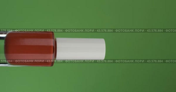 Горизонтальное вращение стеклянной бутылки с лаком для ногтей на зеленом экране. Крупный план. Макияж и косметический предмет. Стоковое видео, видеограф Александр Собко / Фотобанк Лори