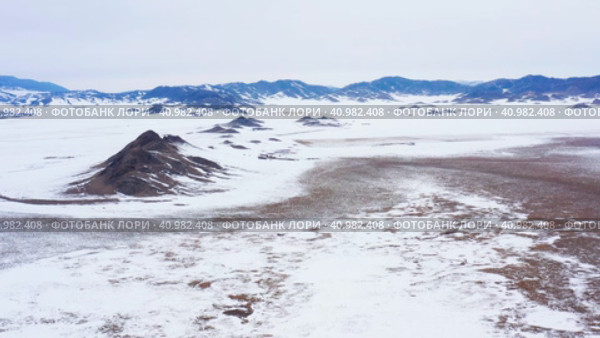 Горный Алтай зимой: одинокая гора в степи. Вид с воздуха. Altai mountains in winter: a lonely mountain among the steppe. Aerial view. Стоковое видео, видеограф Евгений Романов / Фотобанк Лори