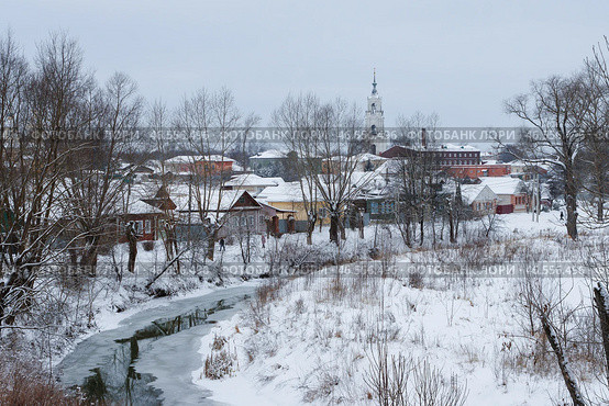 Город Нерехта, Костромская область, Россия. Вид на заснеженный берег реки Нерехты и разноцветные жилые дома. Вдали видна высокая колокольня Казанского собора. Красивый зимний пейзаж. Холодная погода. Стоковое фото, фотограф Андрей Степанов / Фотобанк Лори