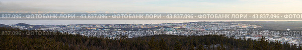 Город Северобайкальск, Республика Бурятия, Сибирь, Россия. Вид сверху на город Северобайкальск, расположенный на берегу озера Байкал. Зимний пейзаж. Вдали заснеженные горы. Озеро покрыто льдом. На переднем плане лес на горном склоне. Широкая панорама. Стоковое фото, фотограф Андрей Степанов / Фотобанк Лори