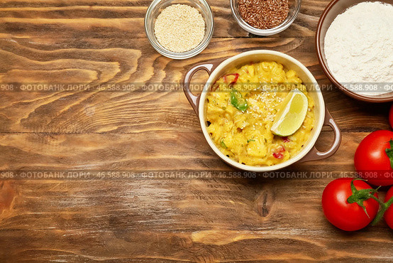 Горшочек с вкусным куриным карри и ингредиентами на деревянном фоне. Стоковое фото, фотограф Pixel_shot / Фотобанк Лори