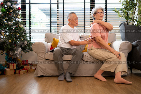 Grandfather and grandmother are giving each other a relaxing massage while waiting to meet their children and grandchildren, who will join them for a meal during the Christmas holiday at home. Стоковое фото, агентство Ingram Publishing / Фотобанк Лори