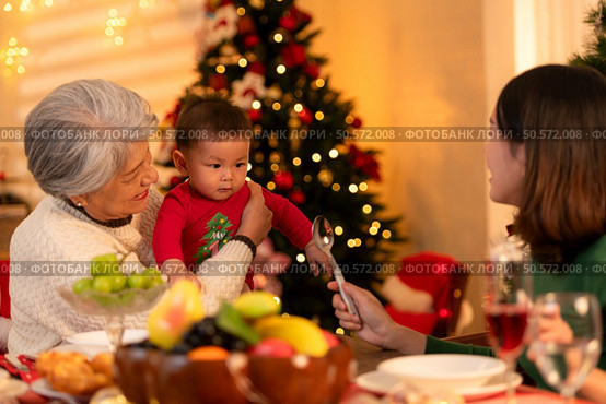 Grandmother, mother and little boy celebrate happily on Christmas night. Стоковое фото, агентство Ingram Publishing / Фотобанк Лори