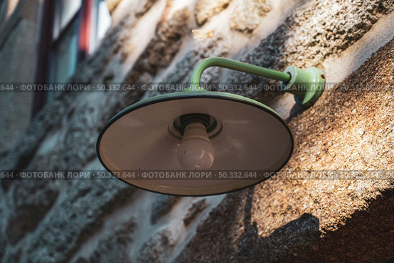 Green ld industrial style lamp on granite wall. Стоковое фото, агентство Ingram Publishing / Фотобанк Лори