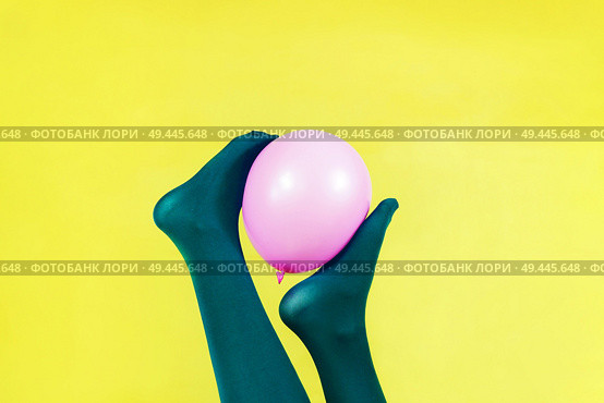 Green legs of a woman holding a pink balloon against a yellow wall                               . Стоковое фото, агентство Ingram Publishing / Фотобанк Лори