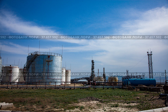 Grey oil storage tanks on bright sun on blue sky with light clouds. Oil refinery plant in desert. Near Taraz city, Kazakhstan. Стоковое фото, фотограф Alexey Rezvykh / Фотобанк Лори