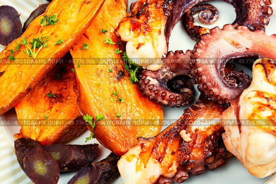 Grilled octopus and baked sweet potato wedges on a plate. Traditional Mediterranean dish. Delicious grilled octopus and sweet potato. Стоковое фото, агентство Ingram Publishing / Фотобанк Лори