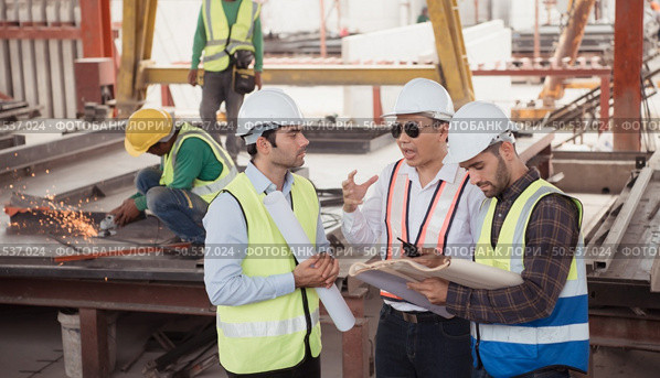 Group of architects, construction foremen, and construction engineers review the work and talk about how the project, in the construction site. Стоковое фото, агентство Ingram Publishing / Фотобанк Лори