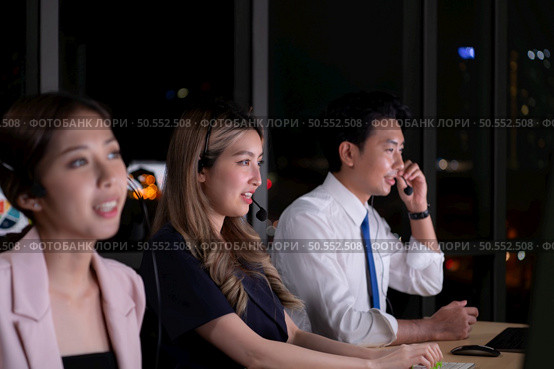 Group of broker international stock traders wearing headset working actively at night in office, Concept of customer support agent provide service on telephone. Стоковое фото, агентство Ingram Publishing / Фотобанк Лори