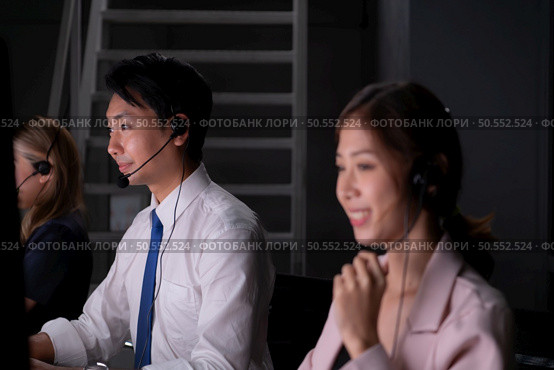 Group of broker international stock traders wearing headset working actively at night in office, Concept of customer support agent provide service on telephone. Стоковое фото, агентство Ingram Publishing / Фотобанк Лори