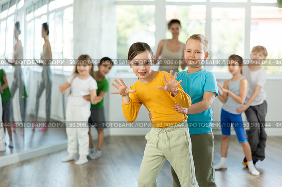 Group of children training movements of twist in dance studio with female teacher. Стоковое фото, фотограф Яков Филимонов / Фотобанк Лори