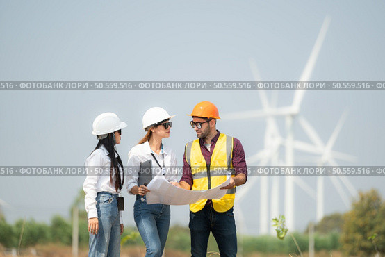Group of engineers and architects on construction site with wind turbines in background. Стоковое фото, агентство Ingram Publishing / Фотобанк Лори