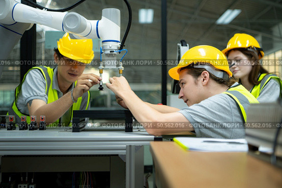 Group of engineers and technicians learning the technology to control hand robots for industrial usage. Стоковое фото, агентство Ingram Publishing / Фотобанк Лори