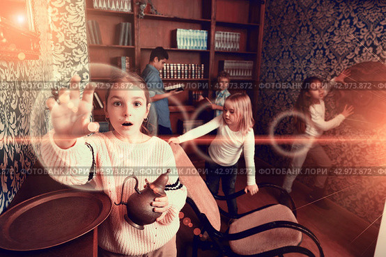 Group of friends trying to find solution of quest in escape room with antique furnitures. Стоковое фото, фотограф Яков Филимонов / Фотобанк Лори