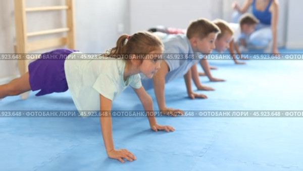 Group of little children doing push-ups on sports mats during a self-defense class in a gym. Стоковое видео, видеограф Яков Филимонов / Фотобанк Лори
