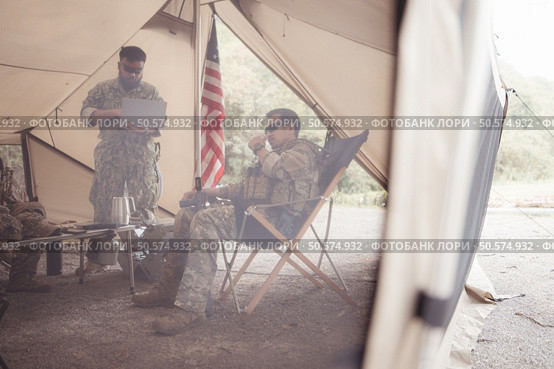 Group of soldiers in camouflage uniforms hold weapons in a field tent, Plan and prepare for combat training. Стоковое фото, агентство Ingram Publishing / Фотобанк Лори