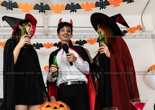 Group of young adult and teenager people celebrating a Halloween party carnival Festival in Halloween costumes drinking alcohol beer singing a song and dancing. Стоковое фото, агентство Ingram Publishing / Фотобанк Лори