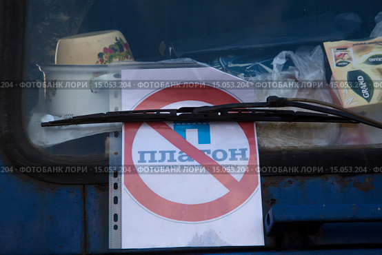 Грузовой автомобиль стоит с плакатом против введения дополнительной платы на федеральных дорогах для грузовых перевозчиков (система "Платон") на парковке дальнобойщиков в пригороде, Россия (2015 год). Редакционное фото, фотограф Николай Винокуров / Фотобанк Лори