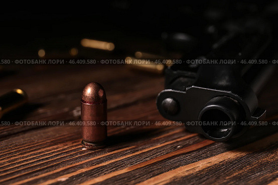 Gun with bullet on wooden table. Стоковое фото, фотограф Pixel_shot / Фотобанк Лори