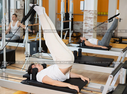 Guy performing reverse crunches with legs raises on Pilates reformer. Стоковое фото, фотограф Яков Филимонов / Фотобанк Лори