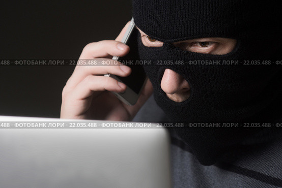 Хакер в маске говорит по мобильному телефону. Стоковое фото, фотограф Mark Agnor / Фотобанк Лори