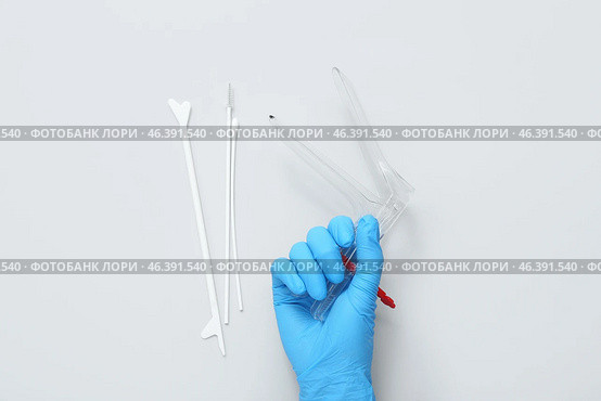 Hand in medical glove, with gynecological speculum and pap smear test tools on light background. Стоковое фото, фотограф Pixel_shot / Фотобанк Лори