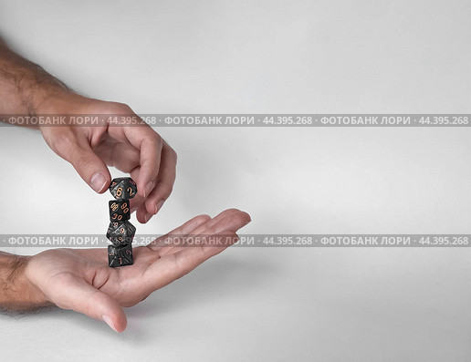 Hands rolling unique polyhedral dice in mid-air against a minimalistic background. Стоковое фото, фотограф Lamina Akulova / Фотобанк Лори