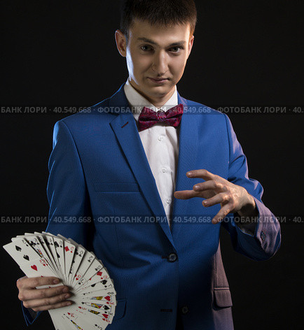 Handsome illusionist showing tricks in the dark. Стоковое фото, фотограф Гурьянов Андрей / Фотобанк Лори