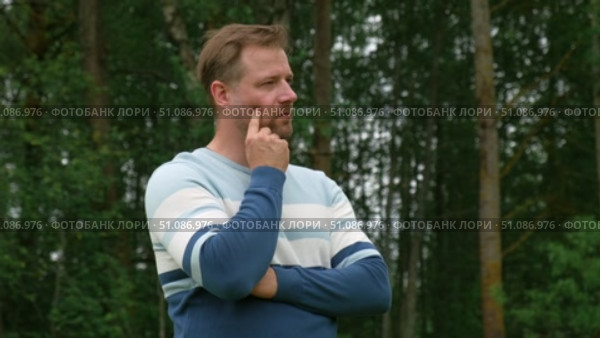 Handsome young man standing outdoors. Male thinking looking around feel happy, calm and serious. Green park background. Guy business employer, businessman manager inspired in nature. Diversity People. Стоковое видео, видеограф Марина Демидюк / Фотобанк Лори