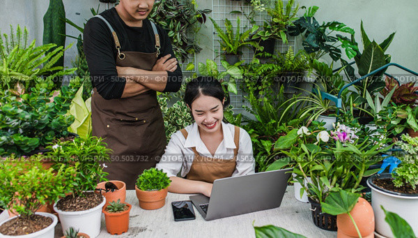 Happily gardener couple use laptop computer while online tutorial on potted plans in workshop together, vlogging or small business houseplant concept. Стоковое фото, агентство Ingram Publishing / Фотобанк Лори