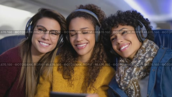 Happy friends watching movie on tablet during flight. Стоковое AI-видео, аниматор Юрий Поздников / Фотобанк Лори